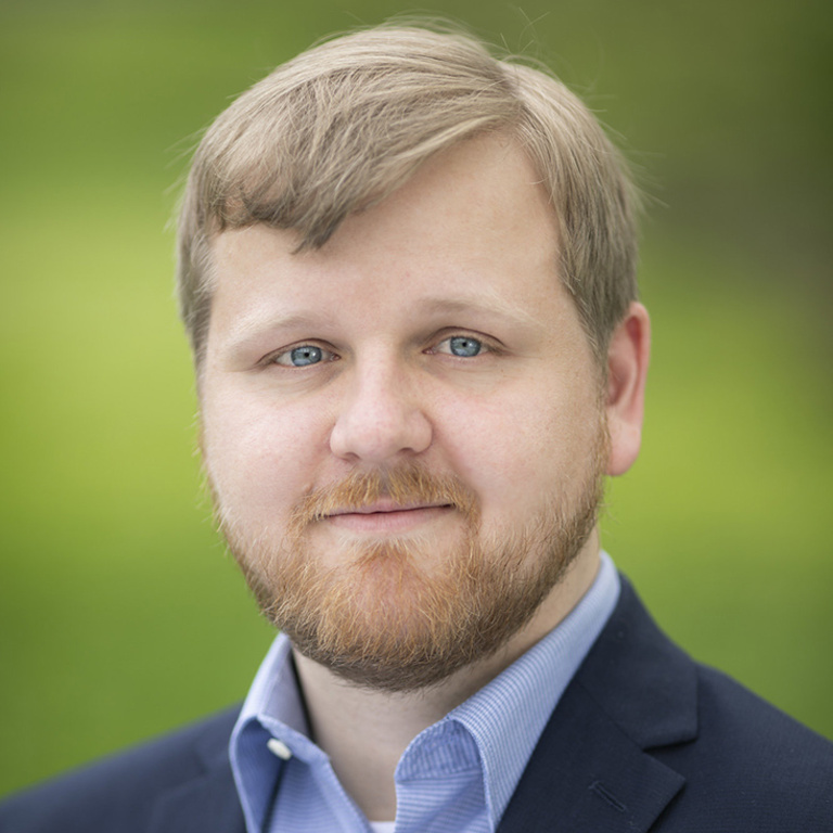 Schöberlein wears a navy blazer and close-cropped blonde hair.