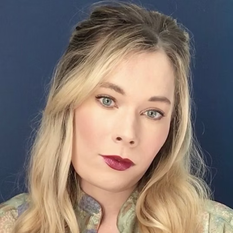 A headshot of a person with long blond hair wearing a green floral shirt